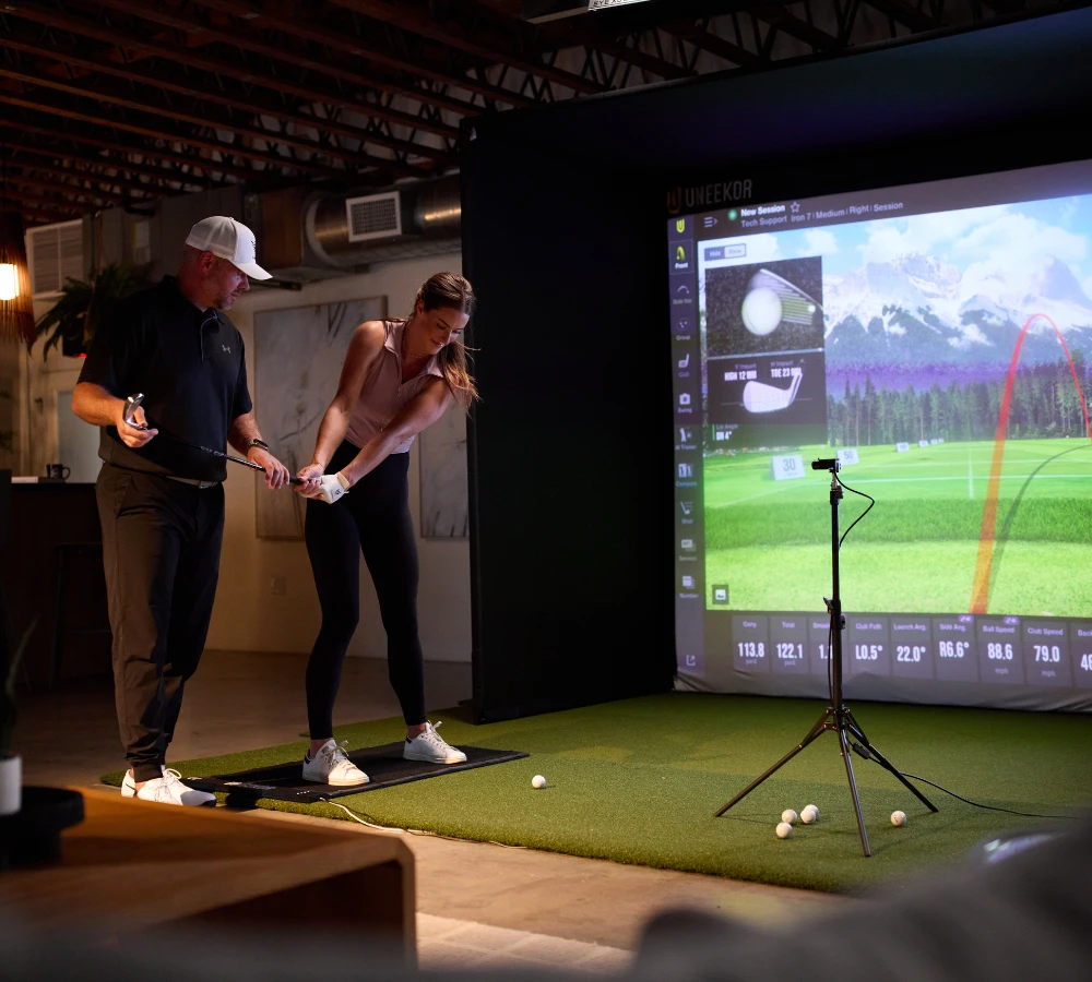 Golfer with trainer playing on Uneekor SIMKIT